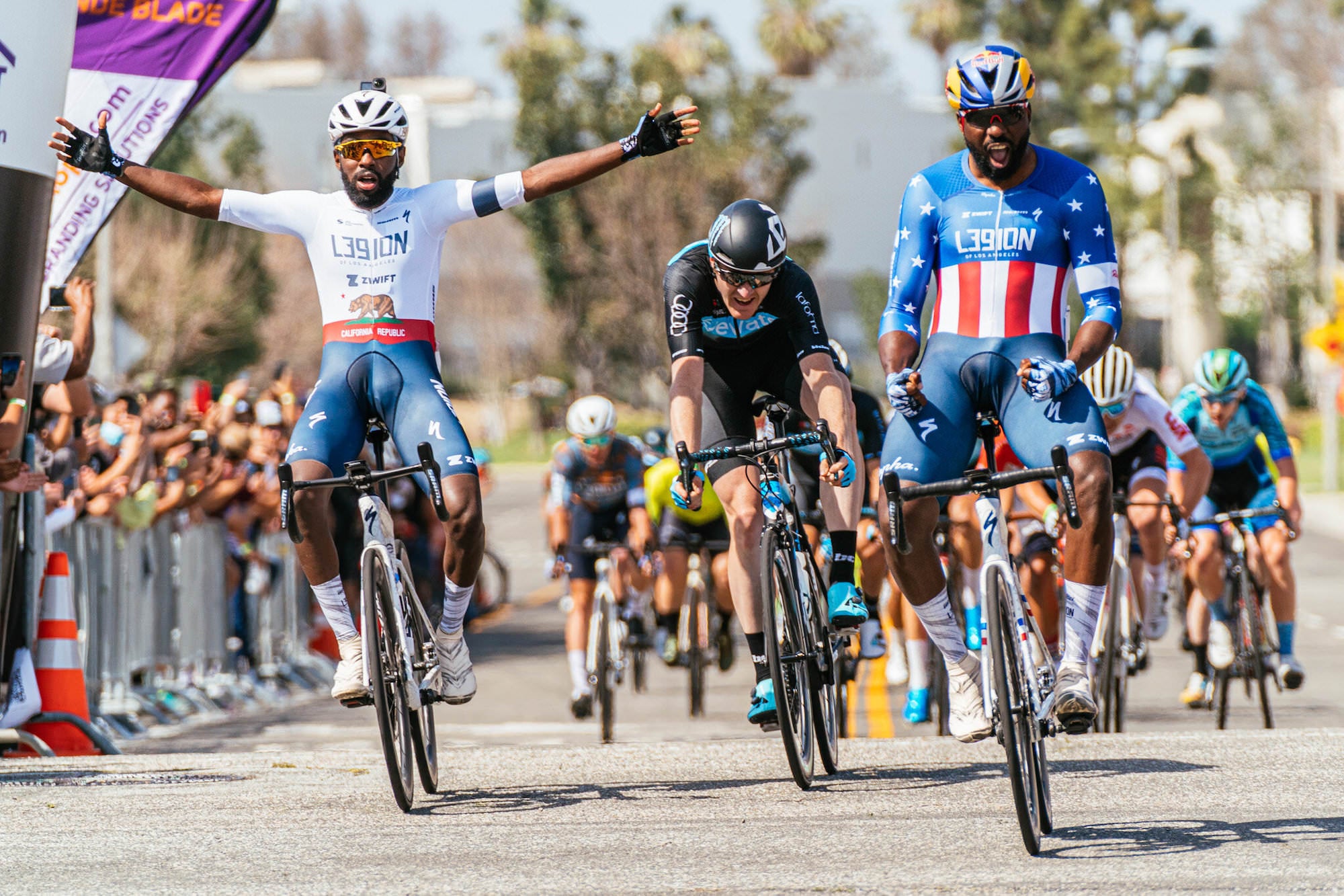 Photo by Kit Karzen. Cyclists cross the finish line. 