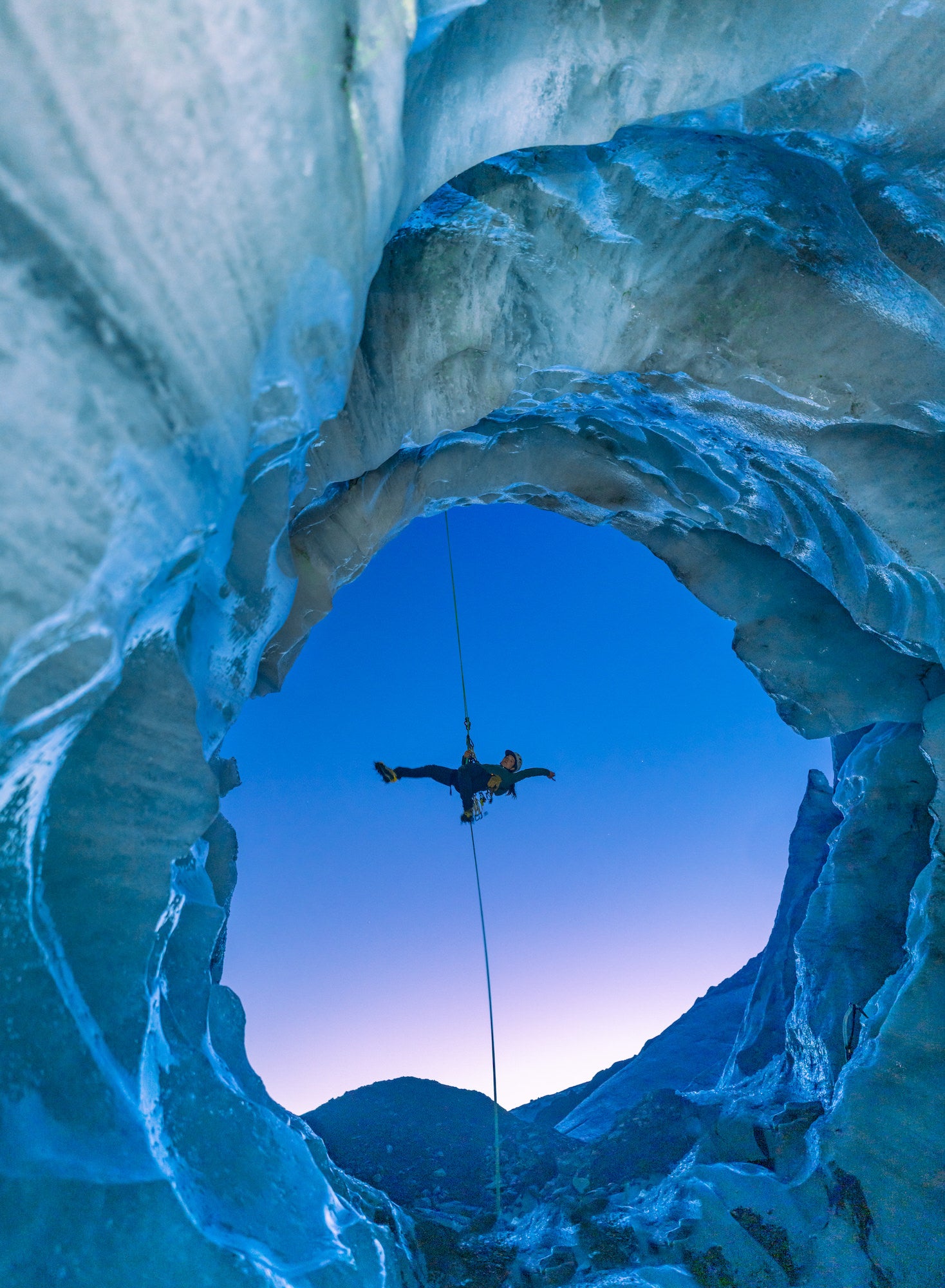 Climber hanging down in ice cave