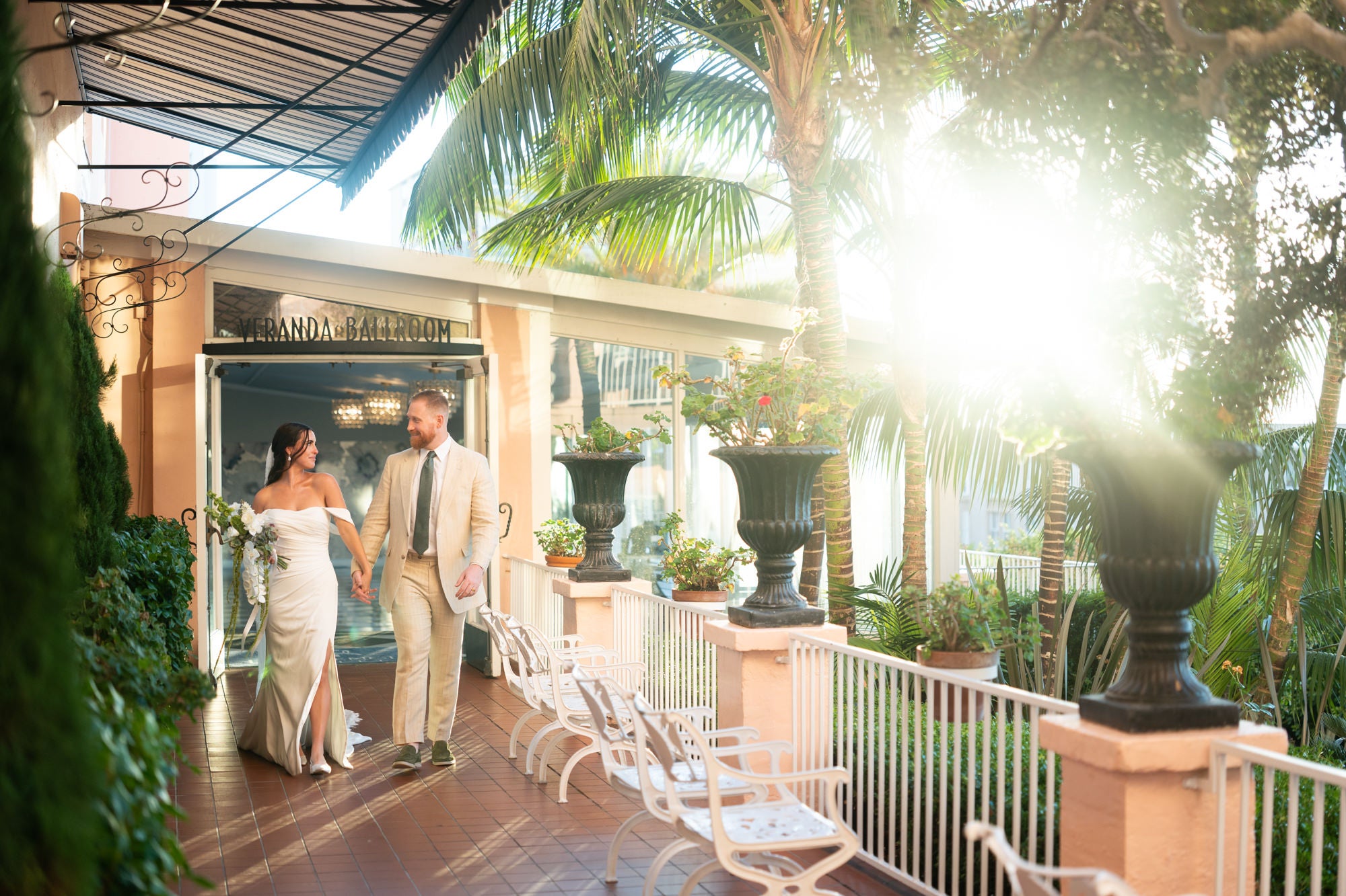 Bride and groom walking together across outdoor ballroom deck at sunset Bride and groom walking together across outdoor ballroom deck at sunset