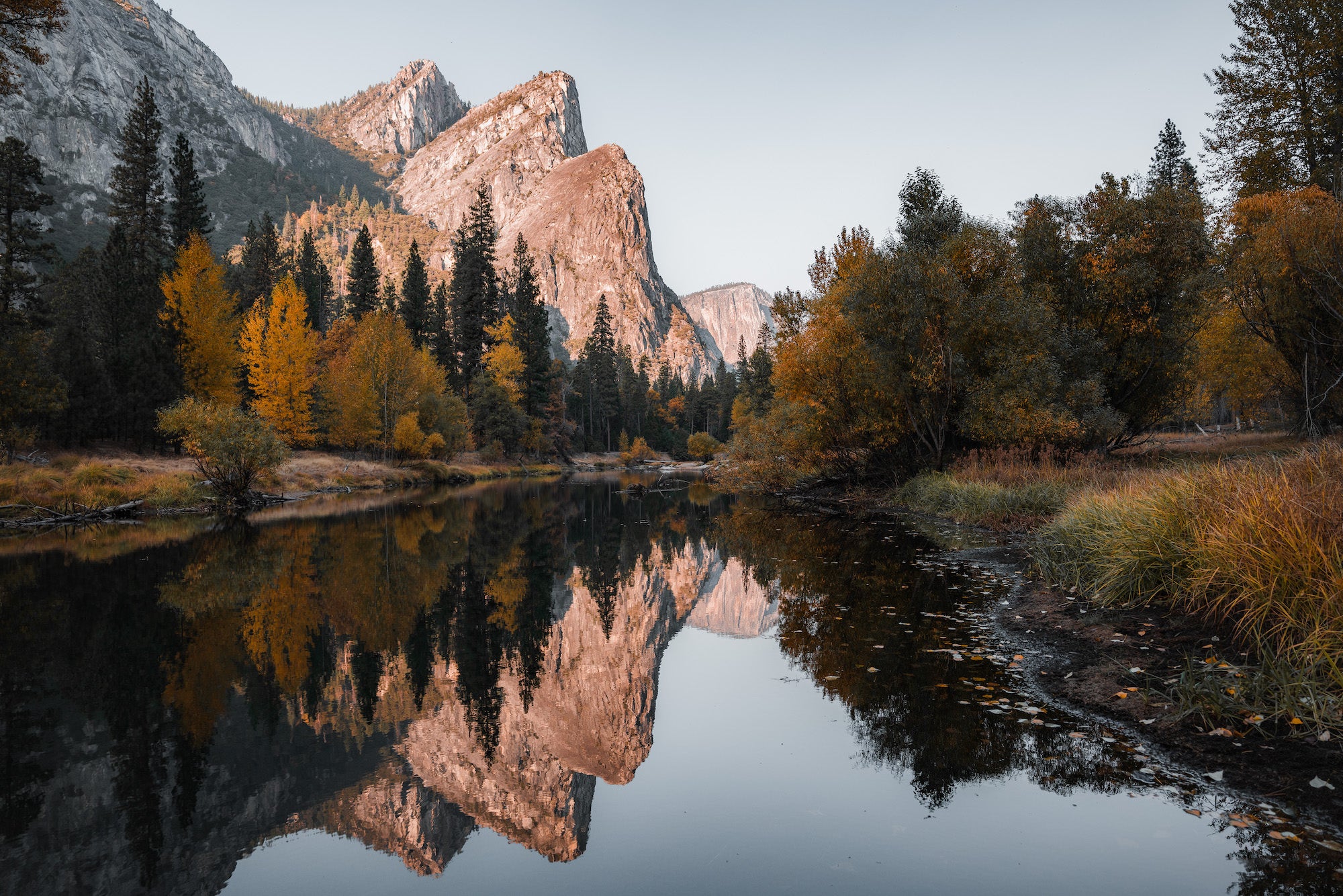 Granite cliffs and autumn trees reflected in a calm river in Yosemite Valley. Granite cliffs and autumn trees reflected in a calm river in Yosemite Valley.