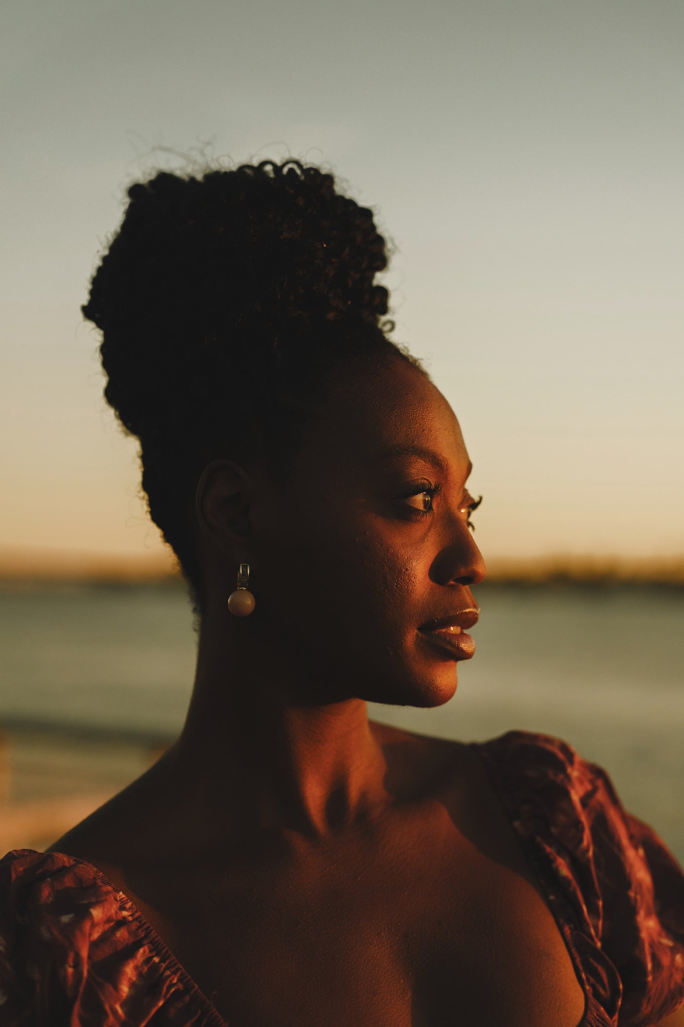 Golden‑hour close-up portrait of a woman in a floral dress, soft coastal light, Sony Creative Space San Diego.