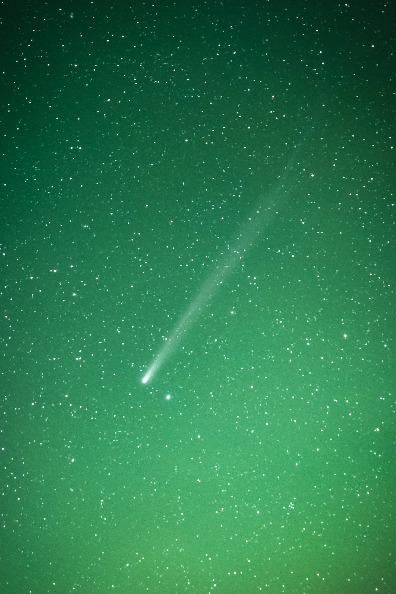 Astro photograph of a comet passing through a green starry sky by Timo Oksanen