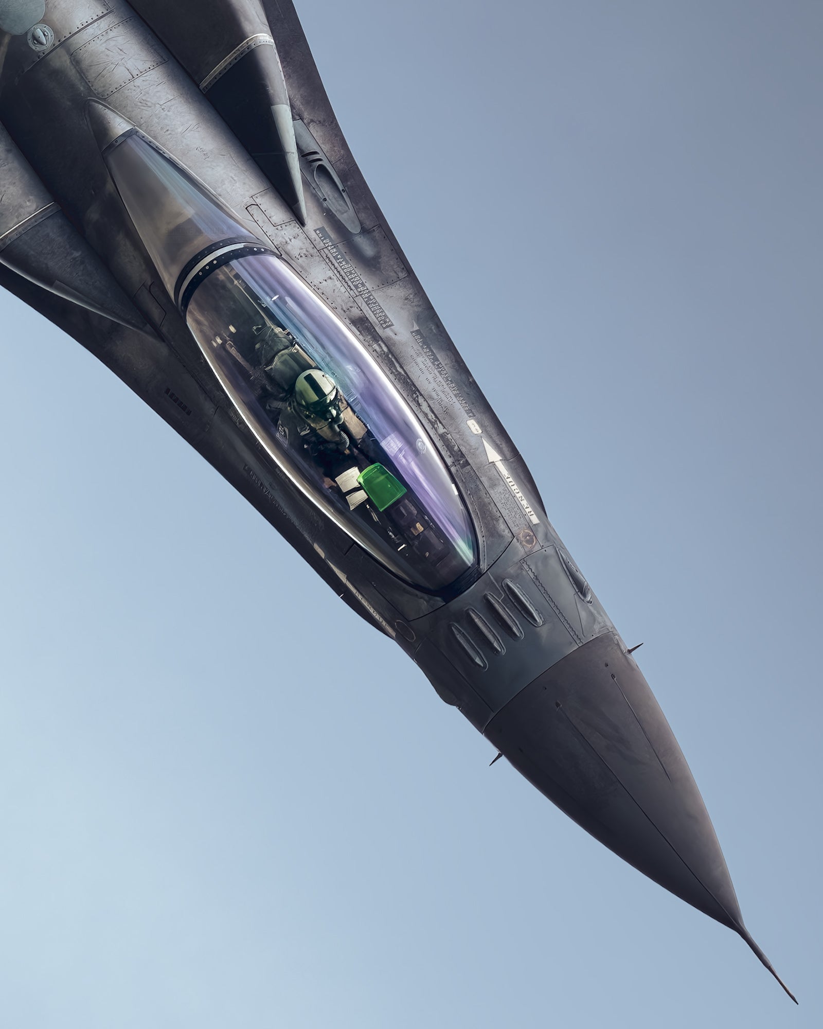 Close-up of a banking fighter jet with the pilot visible through the canopy against a clear blue sky.