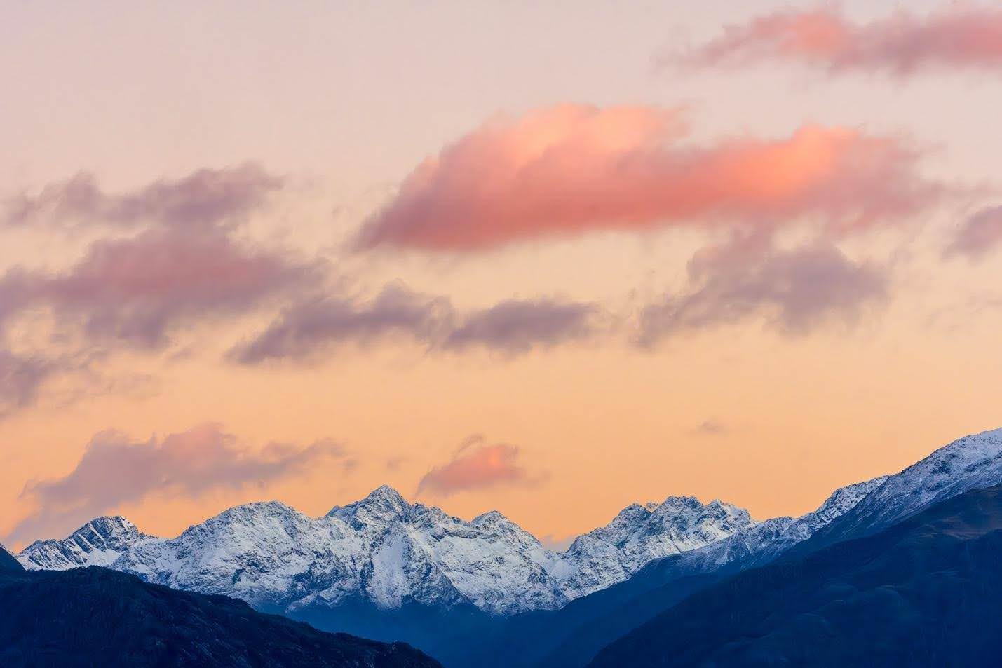 Pastel shades of pink, peach, and lavender wash across the sky at dusk as a snow-covered ridgeline of the Southern Alps rises in cool blue tones in this soft twilight landscape by Don Smith.