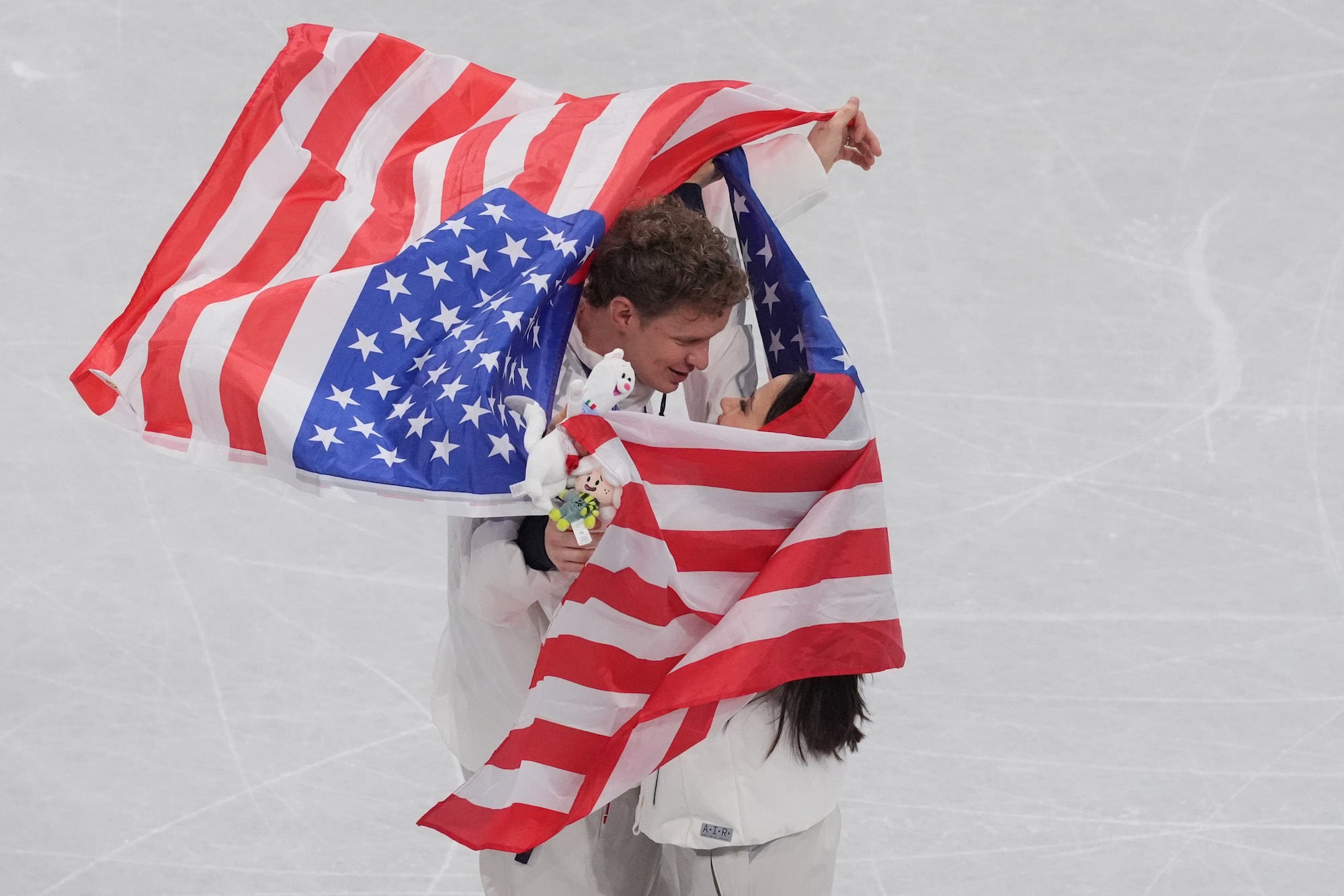 Figure skating pair wrapped in an American flag celebrating on the ice. Figure skating pair wrapped in an American flag celebrating on the ice.