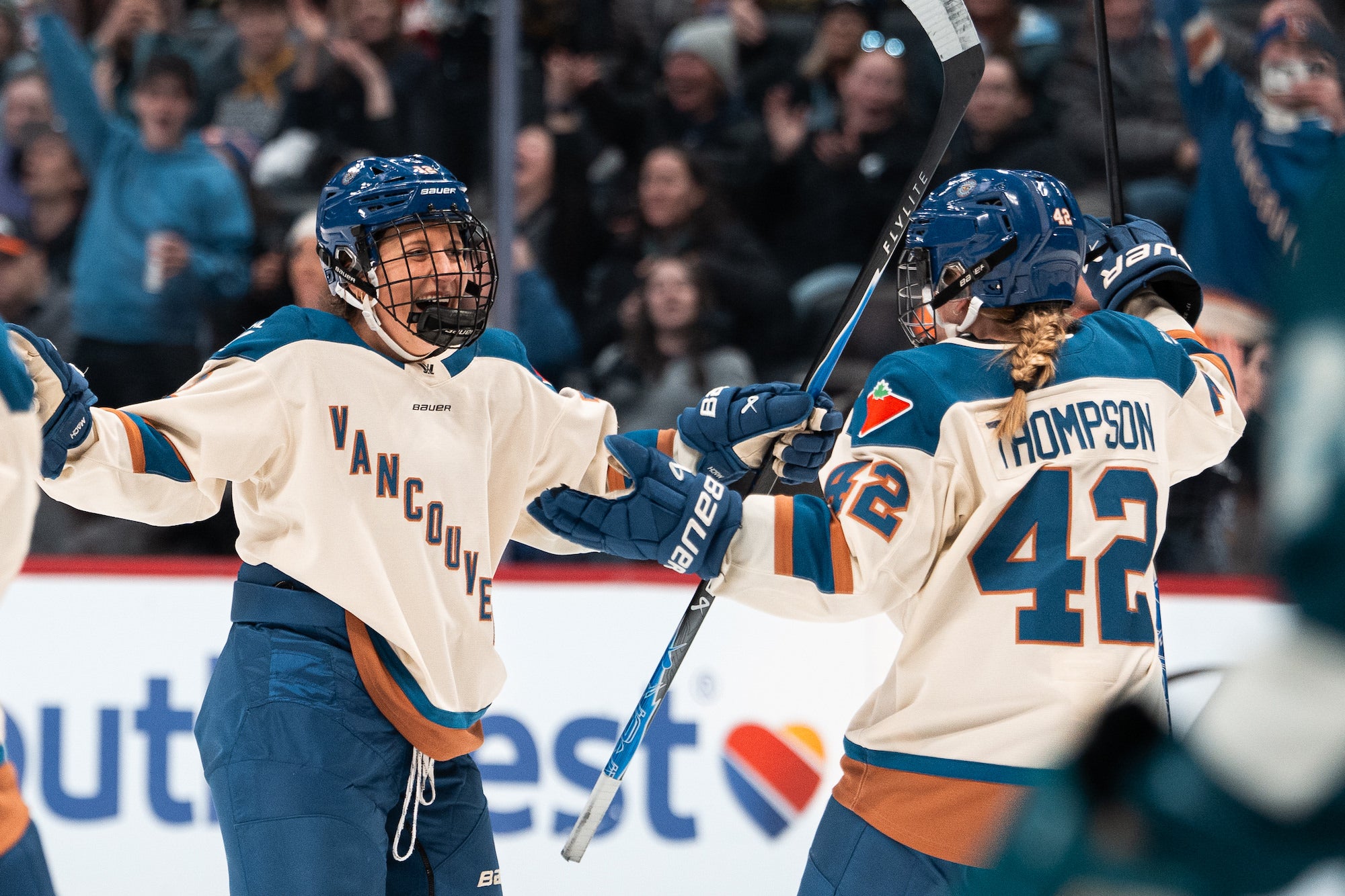Teammates in cream &ldquo;Vancouver&rdquo; jerseys celebrate with arms wide after a goal.