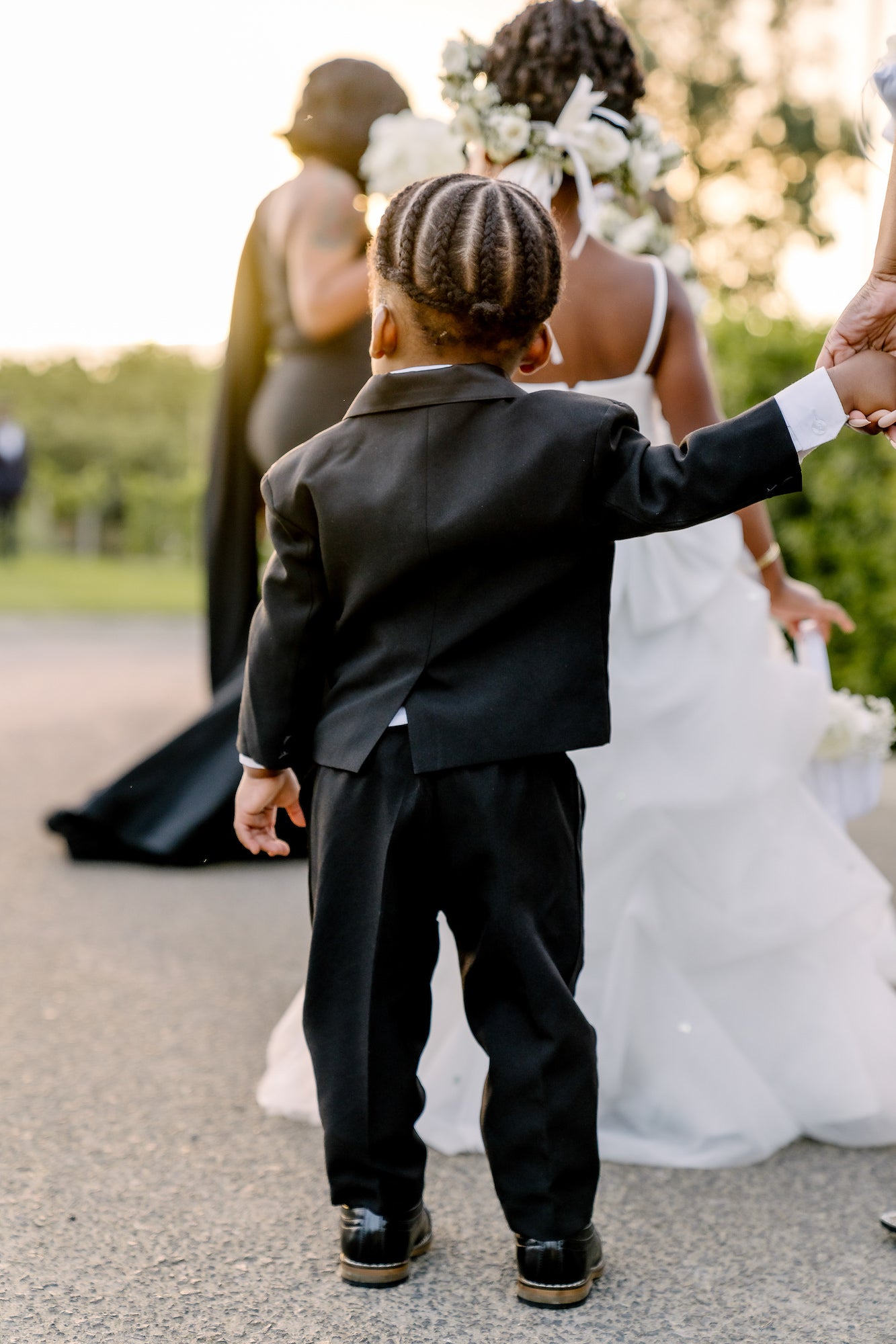 Young man in a suit facing away with an adult holding his hanc Young man in a suit facing away with an adult holding his hanc