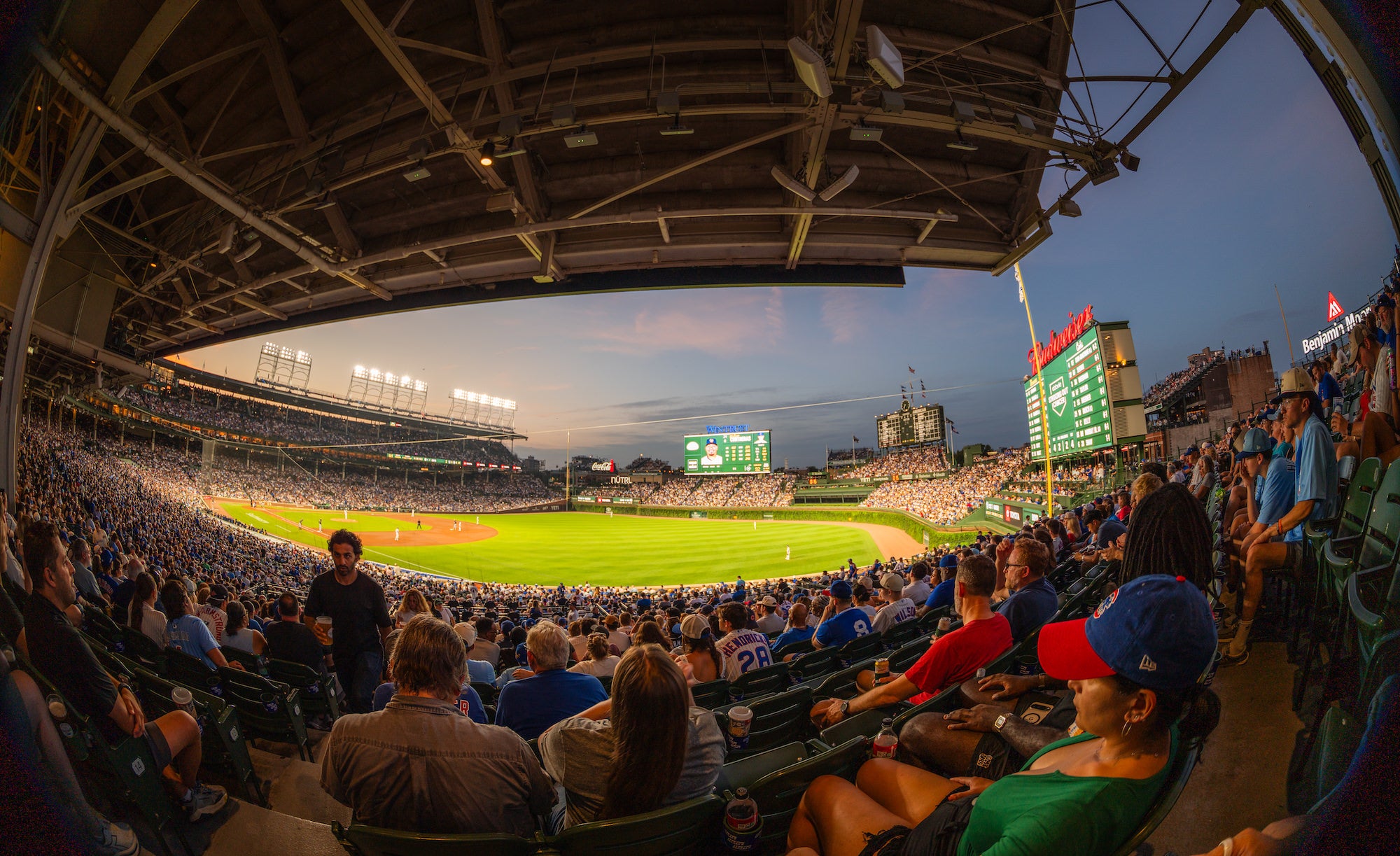 A packed baseball stadium glows at dusk as fans fill the grandstands around a brightly lit field, captured from beneath the sweeping roof with a fisheye lens. Photo by Mike Meyers. Alpha 7R V. 8&ndash;14mm f/3.5 Fisheye G. 1/40-sec. f/3.5. ISO 100.