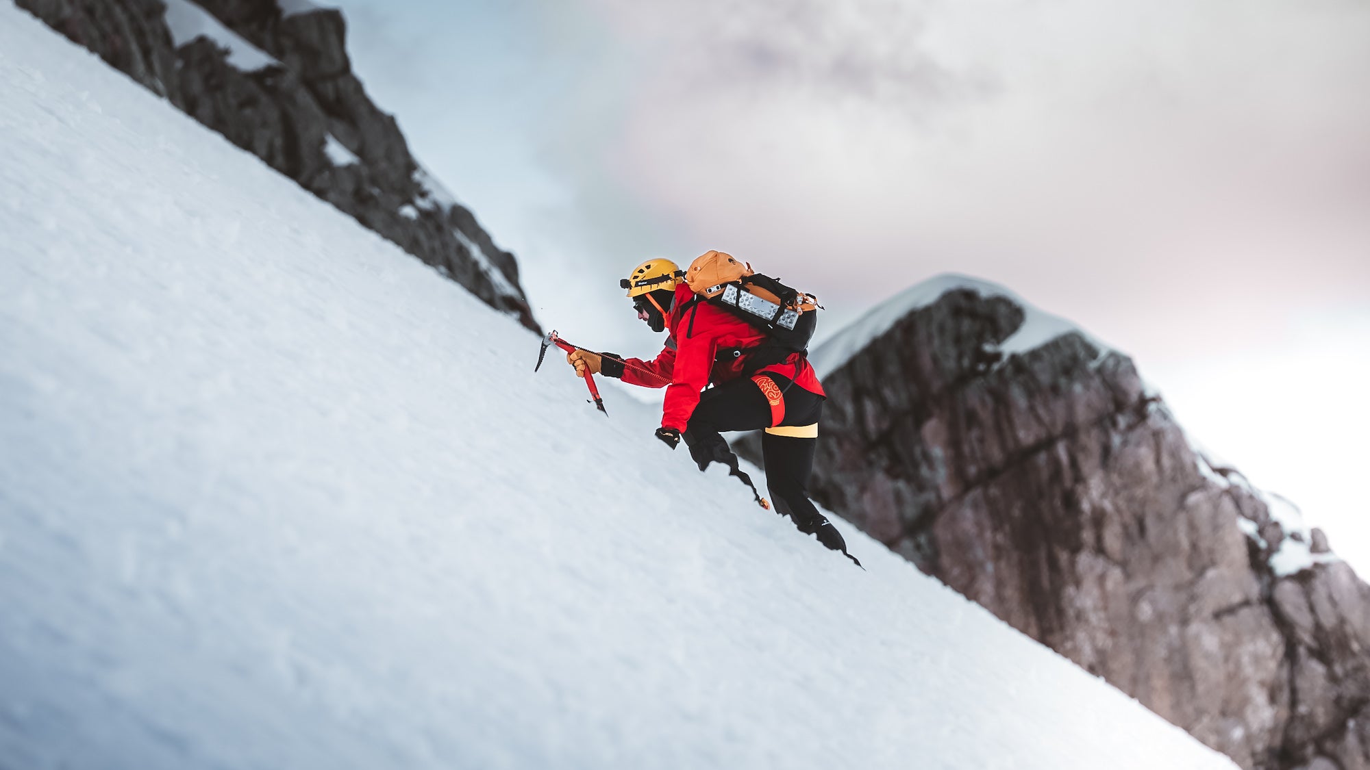 Person using an ice ax to climb a mountain