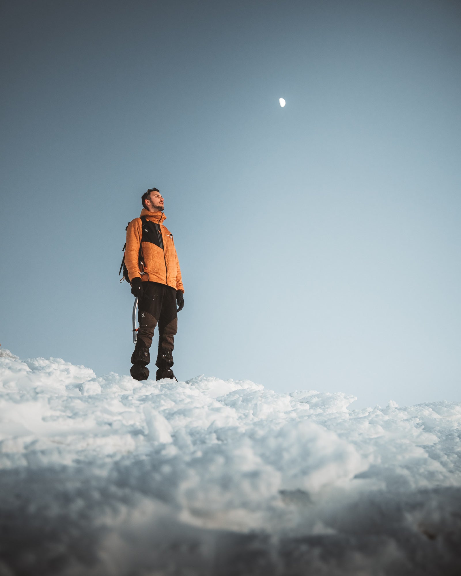 Man standing on snow looking upward at sky