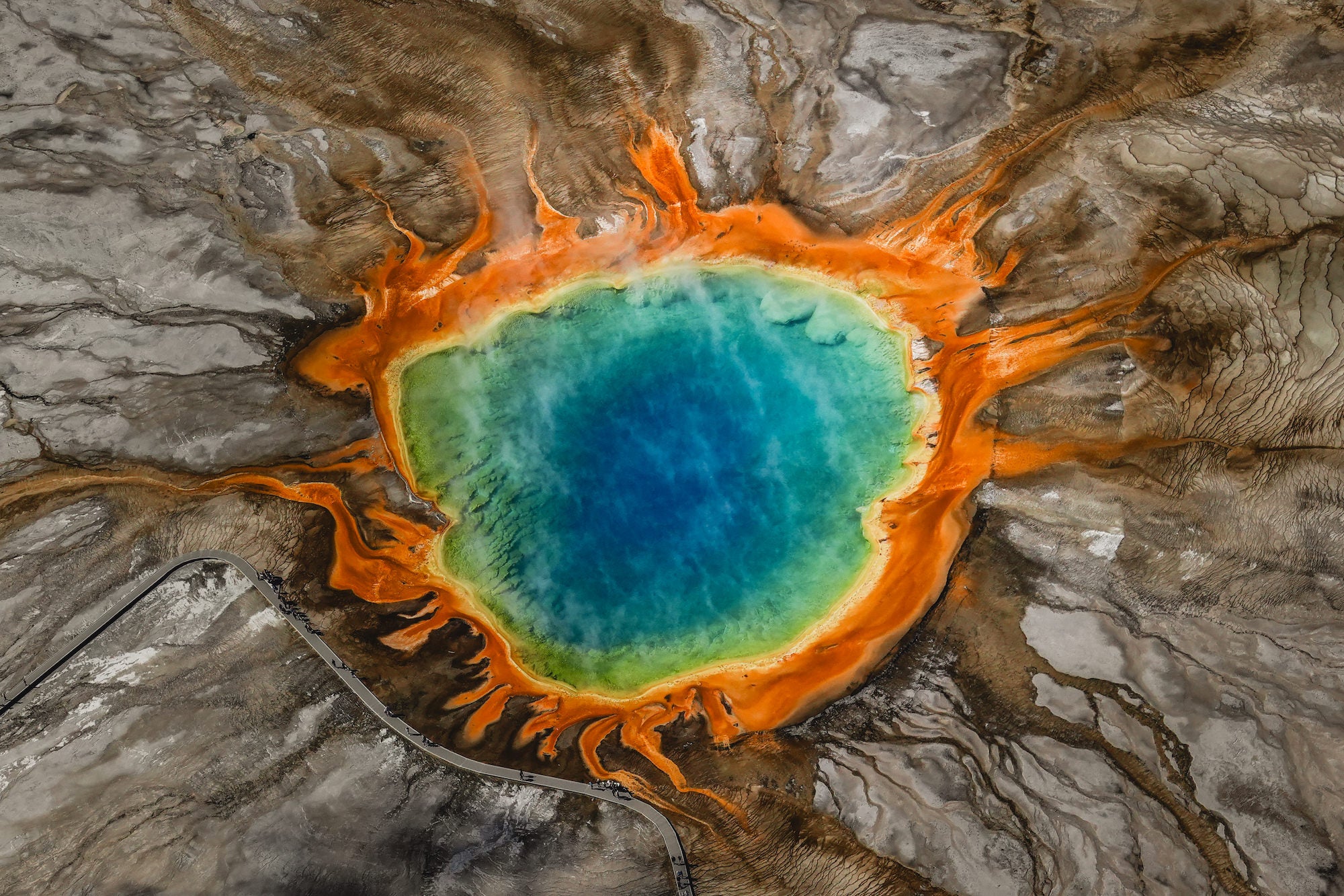 (Grand Prismatic Spring) An aerial perspective reveals the vivid concentric rings of Yellowstone's Grand Prismatic Spring &mdash; deep blue center bleeding into turquoise, then a fiery burst of orange and brown at the edges &mdash; shot from altitude with the Sony RX