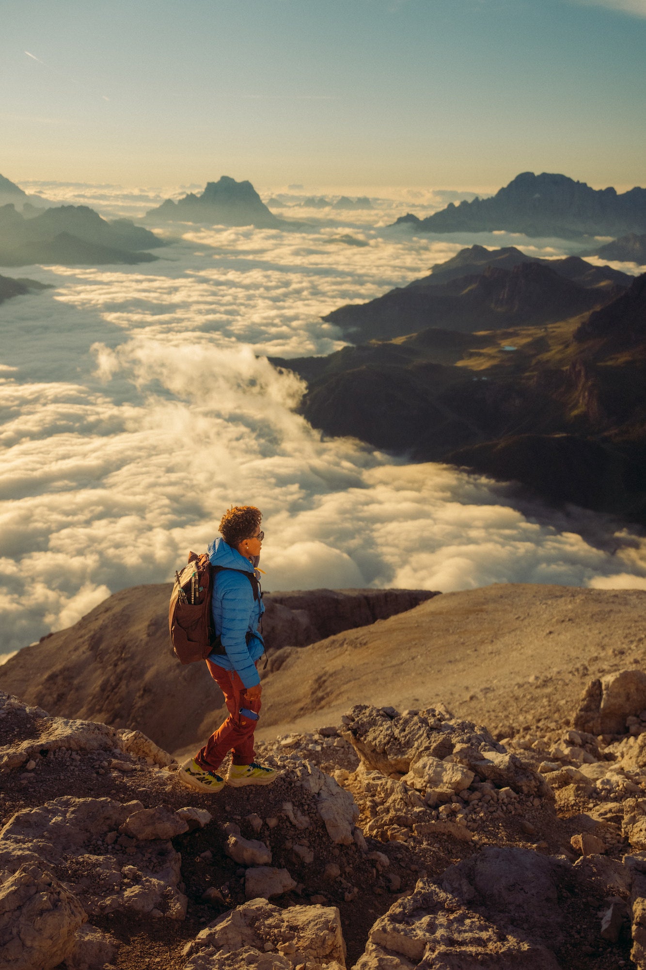 Female hiking through mountain terrain with clouds in the background