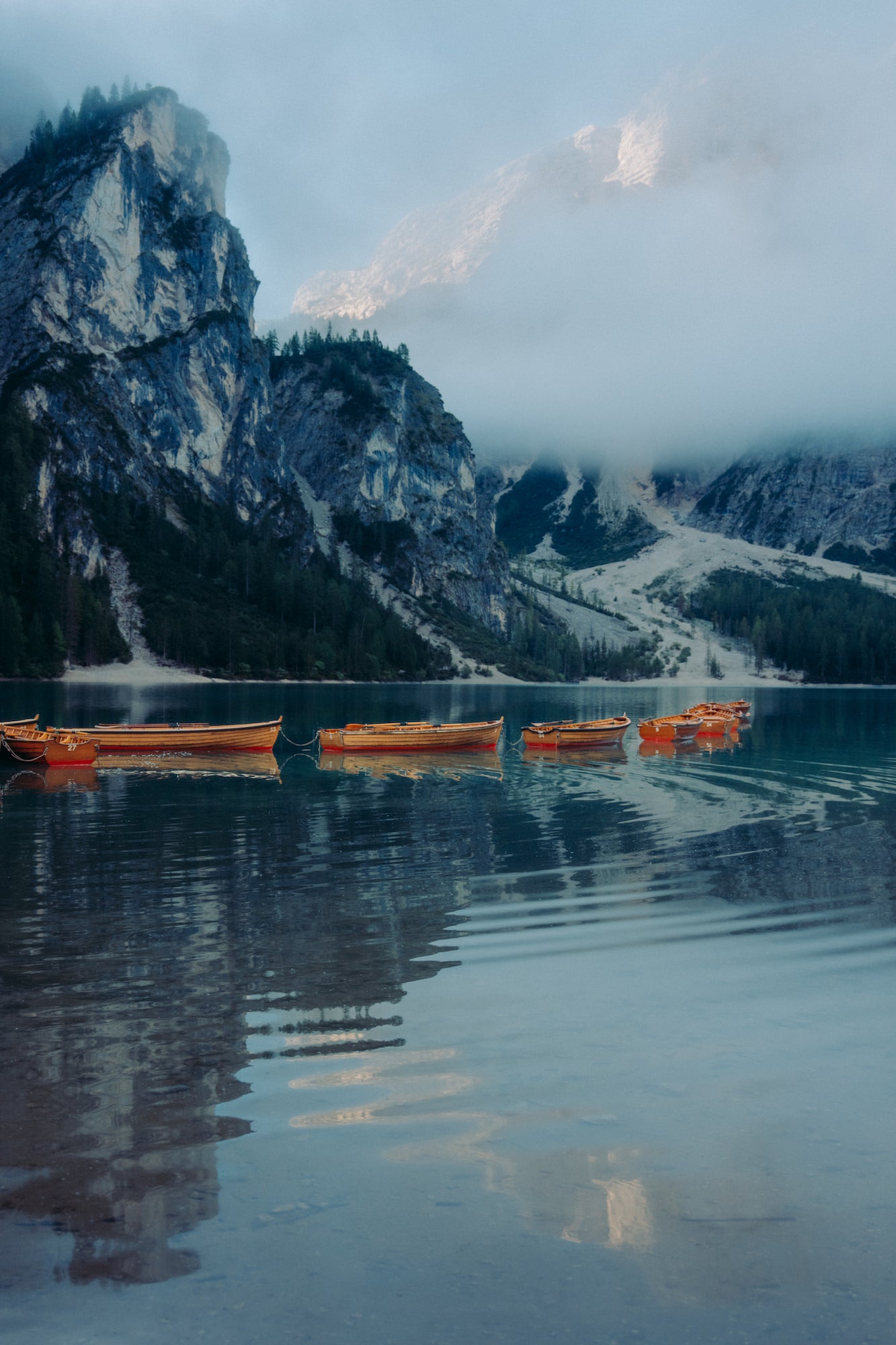Red canoes lined up in a lake with a snowy mountains in the background