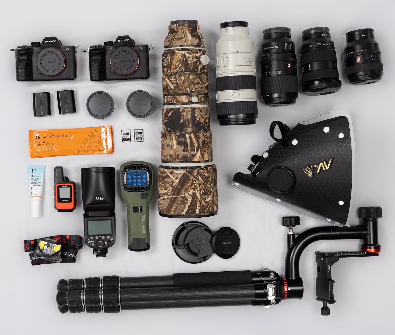Flat lay of a Sony Alpha wildlife kit: A7R V and A7 IV bodies, 200&ndash;600 G (camo cover), 70&ndash;200 GM II, 24&ndash;70 GM II, 50mm, 100mm Macro, teleconverters, tripod, gimbal, flash, GPS, headlamp, batteries, and SD cards.