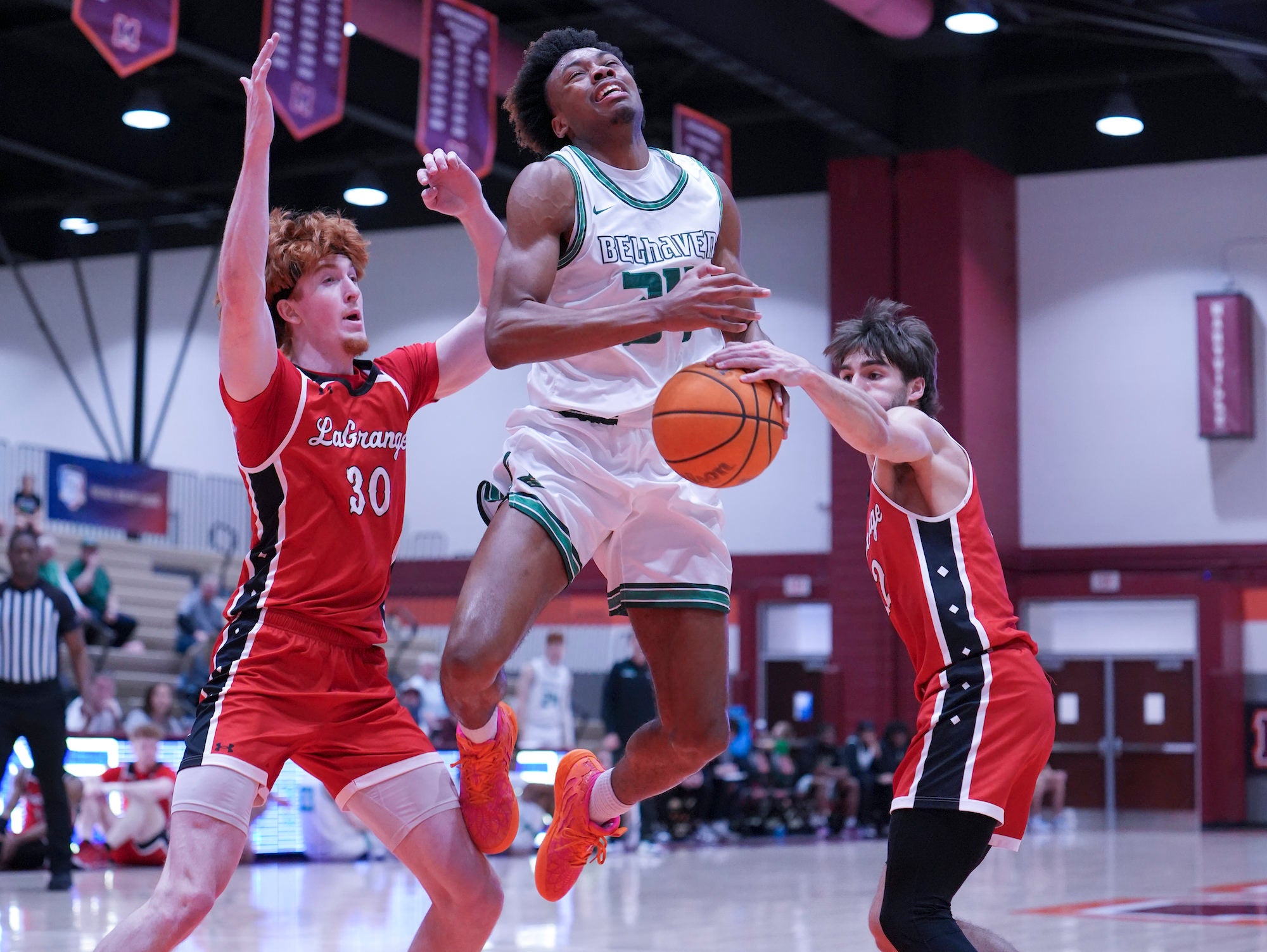 Ballhandler in white squeezed between two defenders, drawing contact