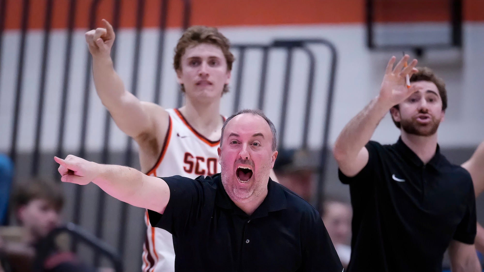 Bench and coach emphatically pointing during intense basketball moment