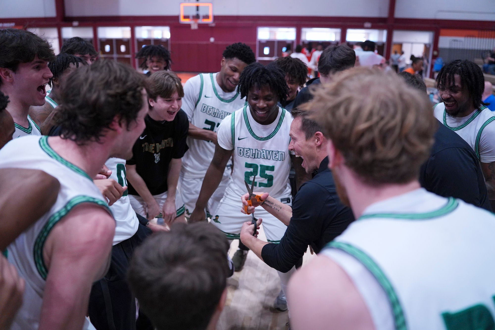 Team in white huddles and celebrates on court after a win