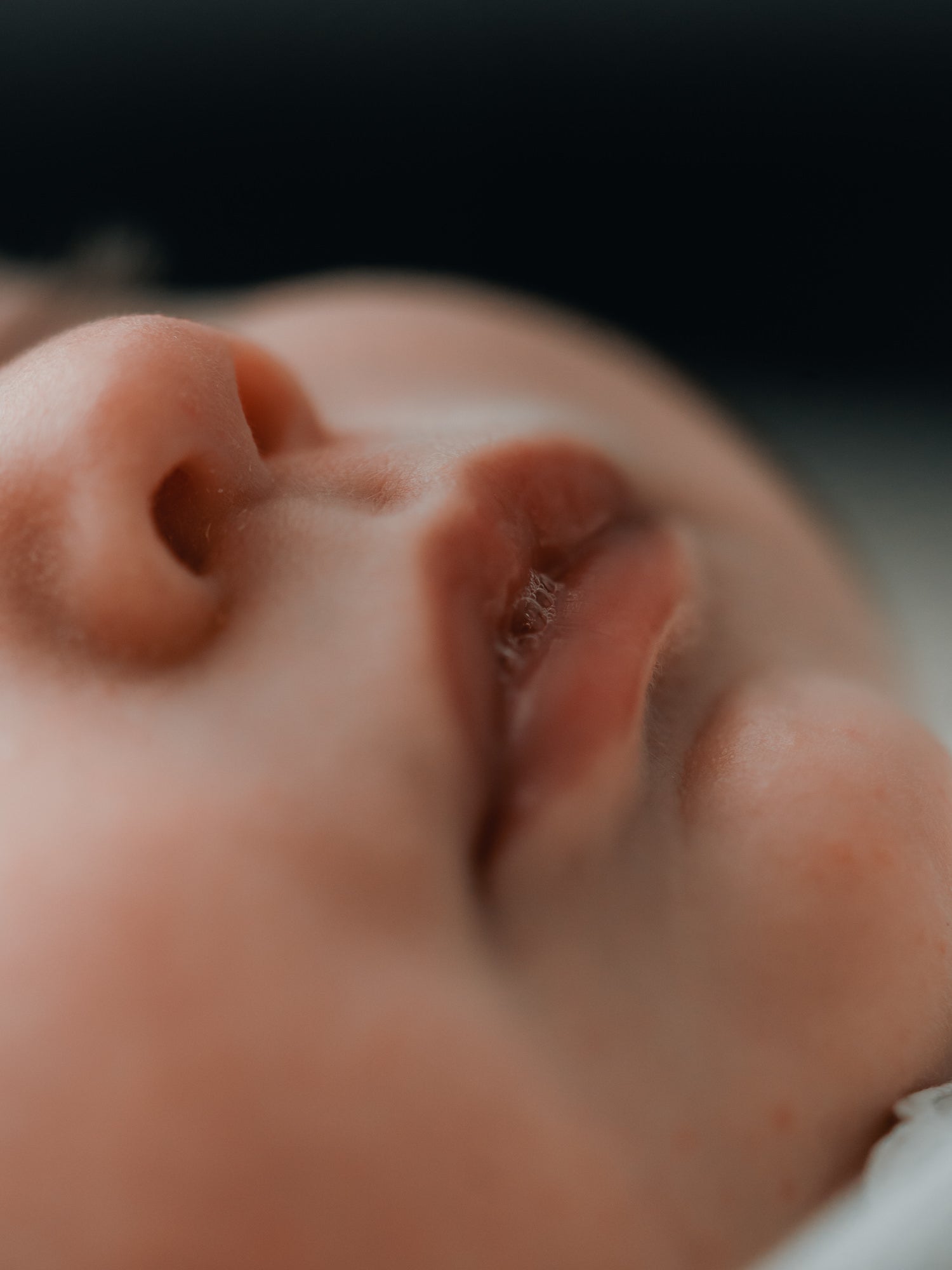 Soft macro of a baby&rsquo;s lips and nose in warm light.