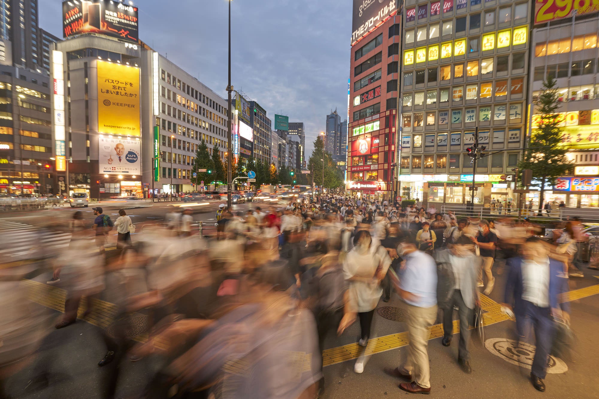 Outdoor corporate portrait of a man in a suit with arms crossed, city street bokeh in warm evening light.