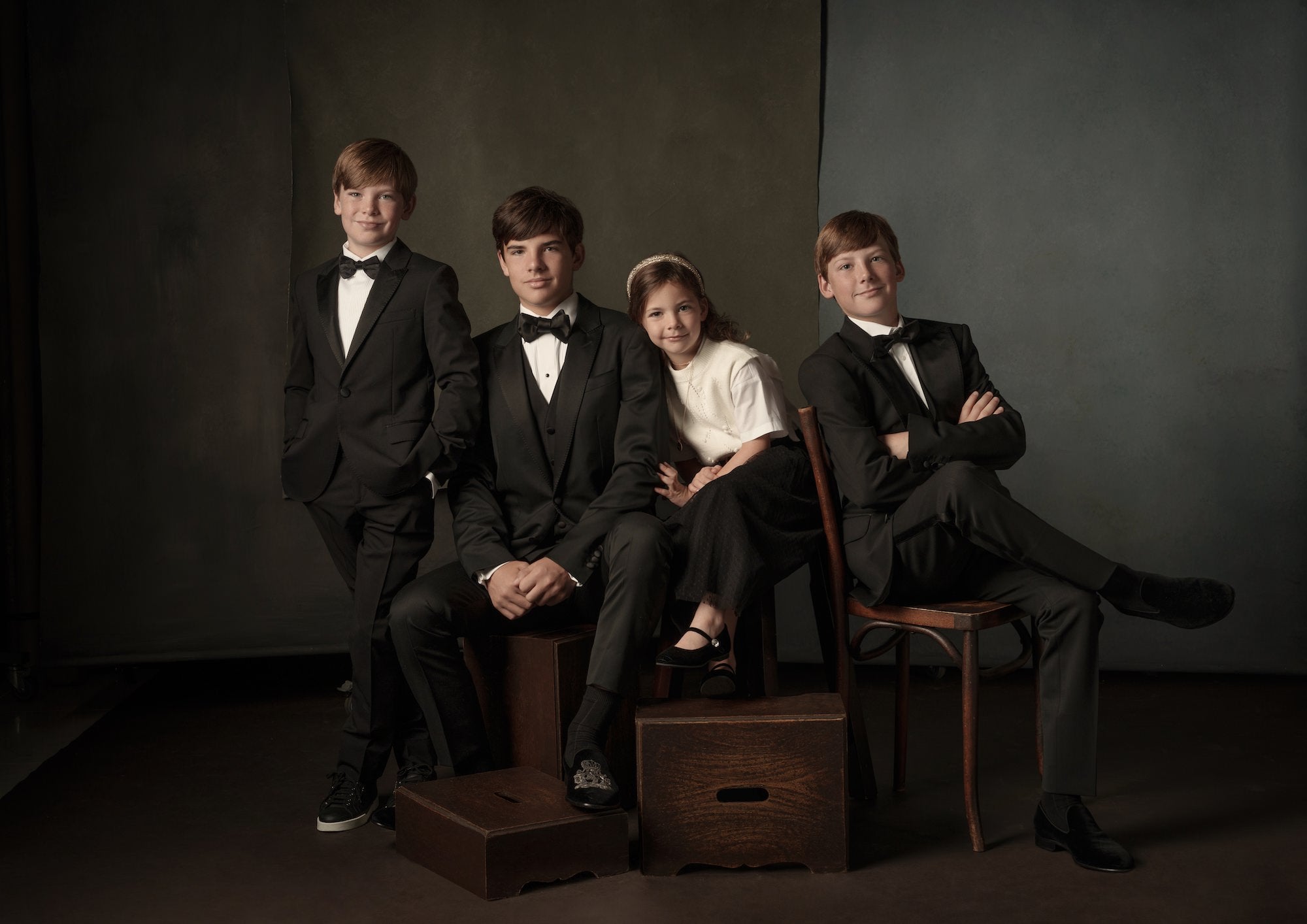 Formal studio group portrait of four kids in tuxes and a girl in a white top and skirt, seated and standing on apple boxes. Formal studio group portrait of four kids in tuxes and a girl in a white top and skirt, seated and standing on apple boxes.
