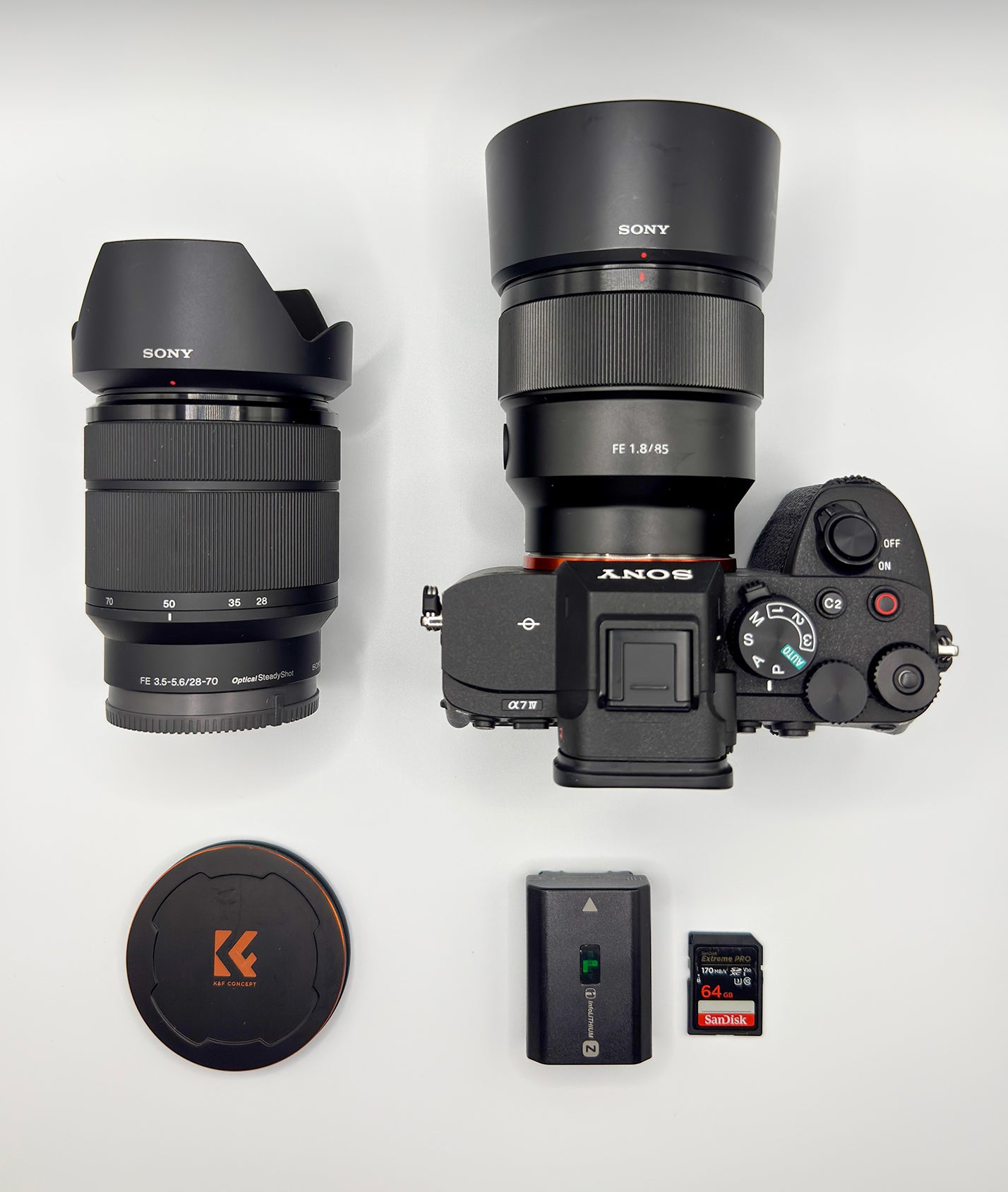 Sony Alpha camera with 85mm, 28–70mm lens, battery and SD cards arranged for a what’s in my bag feature.