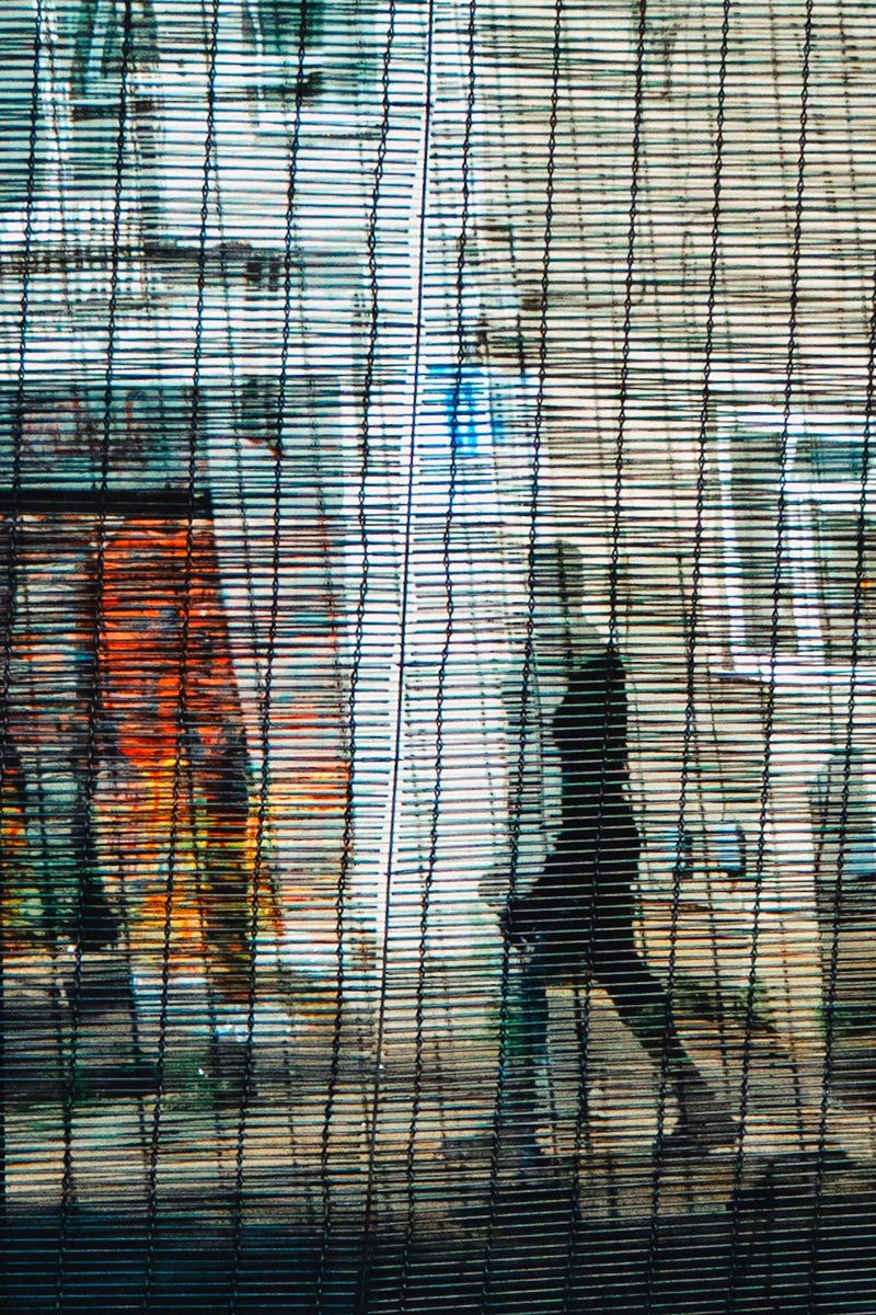 https://alphauniverseglobal.media.zestyio.com/urban-silhouette-behind-wire-screen-reflection-street-scene.jpg?height=1200&fit=bounds